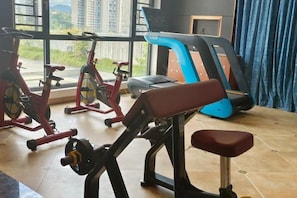 Un gimnasio con máquinas de cardio, una banca y una cinta de correr.
