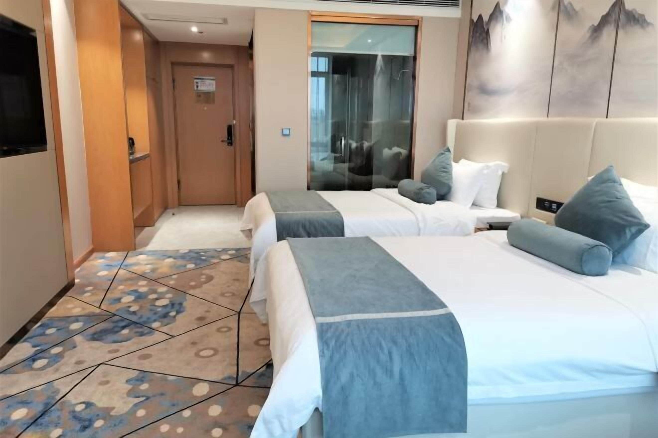 A hotel room with two beds, a large mirror, and a painting on the wall.