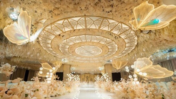 A grand hall with a central circular chandelier, ornate floral arrangements, and a reflective floor. - Xingpeng International Hotel (Huayuan)