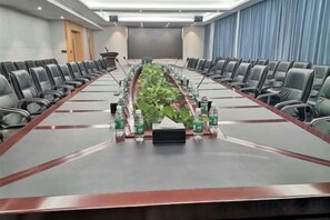 A conference room with a long table, chairs, and a projector screen. - Xingpeng International Hotel (Huayuan)