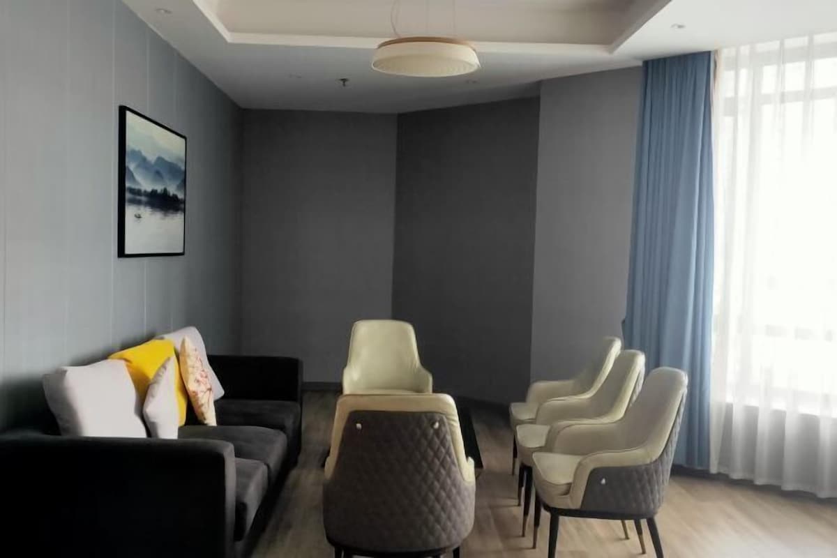 Una sala de estar moderna con un sofá, sillones y un cuadro en la pared.