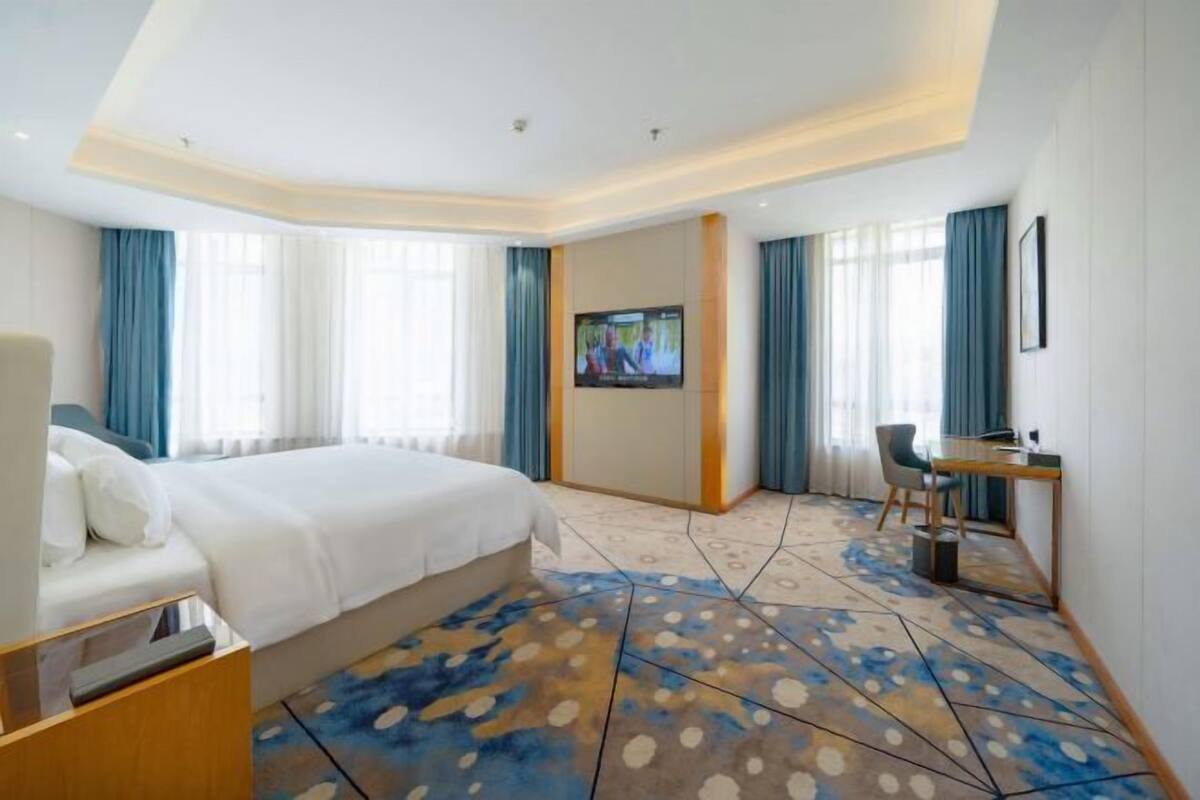 A hotel room with a large bed, a desk, and a TV.