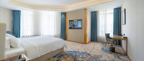 A hotel room with a large bed, a desk, and a TV.