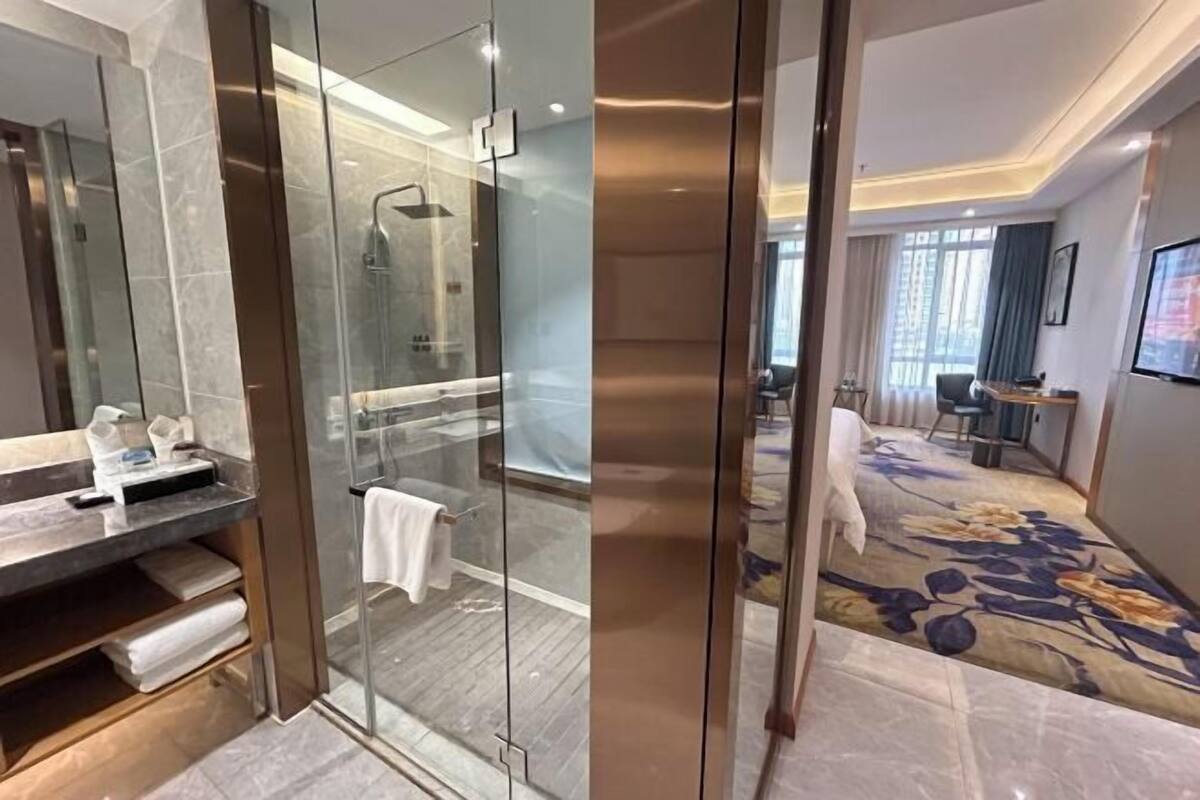 A modern bathroom with a glass-enclosed shower, a marble vanity, and a large mirror.