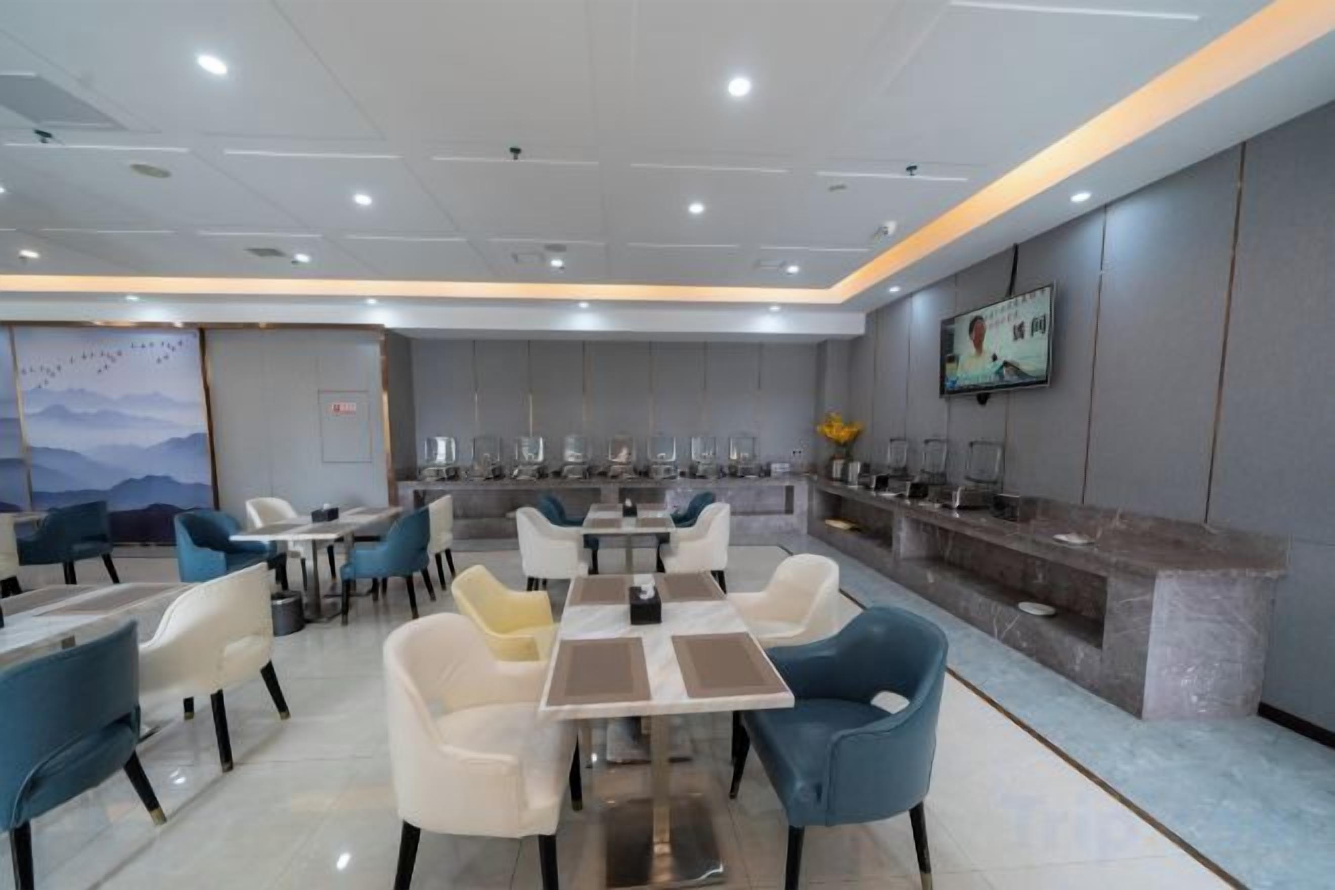 A modern dining area with tables and chairs, a counter with a display, and a wall-mounted television.