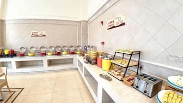 A buffet setup with multiple food stations, a self-service beverage dispenser, and a toaster.