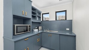 A compact kitchen with grey cabinets, a microwave, a kettle, and a sink. - Spring Hill Inn (Spring Hill)
