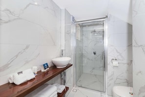 Bathroom features a glass-enclosed shower, pedestal sink, and wooden vanity.