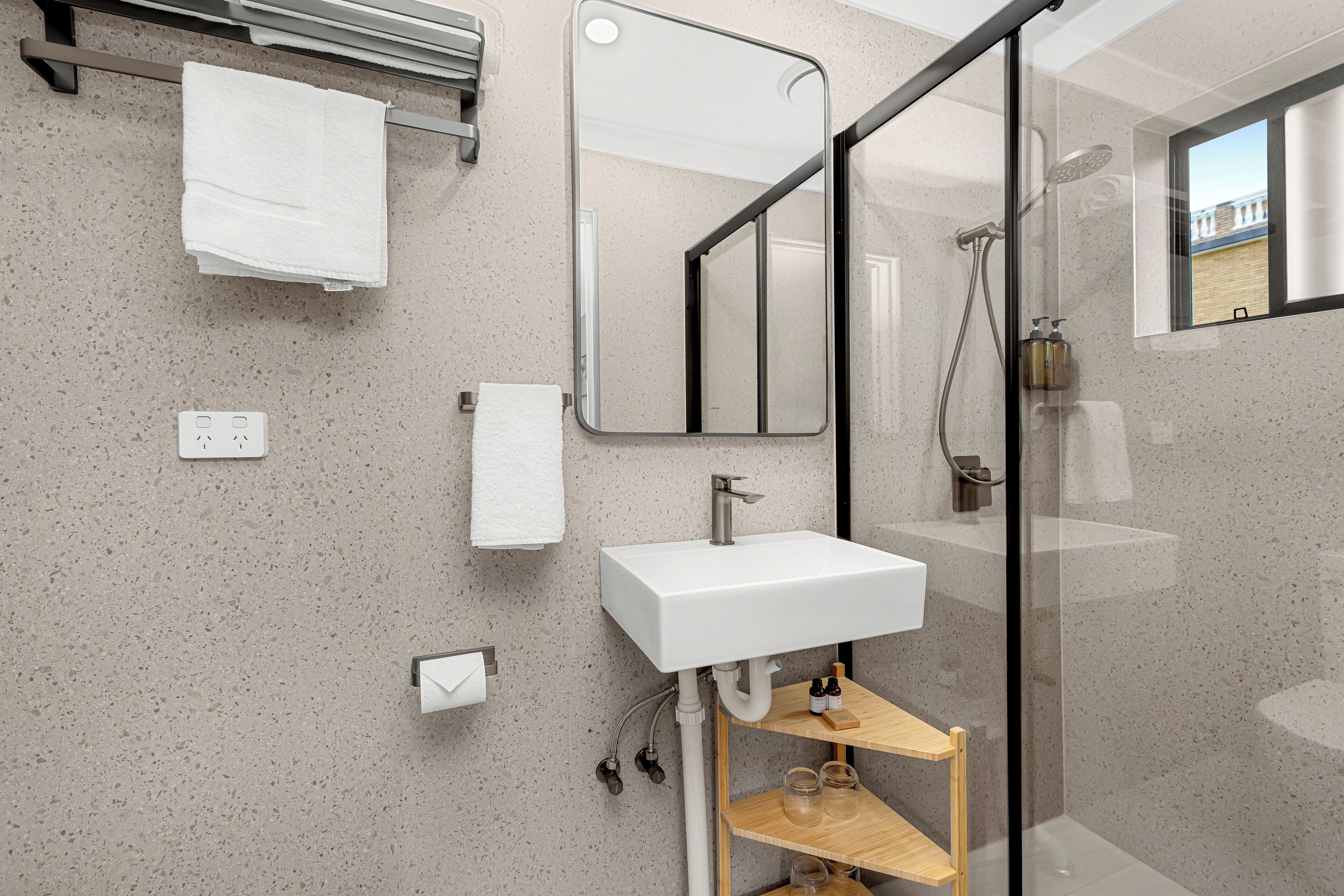 Une salle de bain moderne avec un lavabo blanc, un miroir et une cabine de douche en verre.