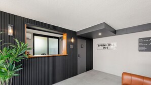 A reception area with a wooden counter, a reception desk, a sign for Spring Hill Inn, and a brown leather couch. - Spring Hill Inn (Spring Hill)