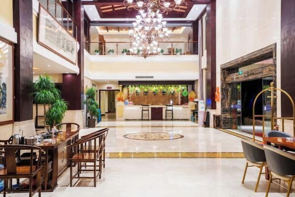 A spacious lobby with a reception desk, a chandelier, and multiple seating areas.