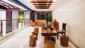 Un vaste espace dédié à la salle à manger, avec une longue table en bois, de nombreux tabourets en bois et un design moderne au niveau du plafond.