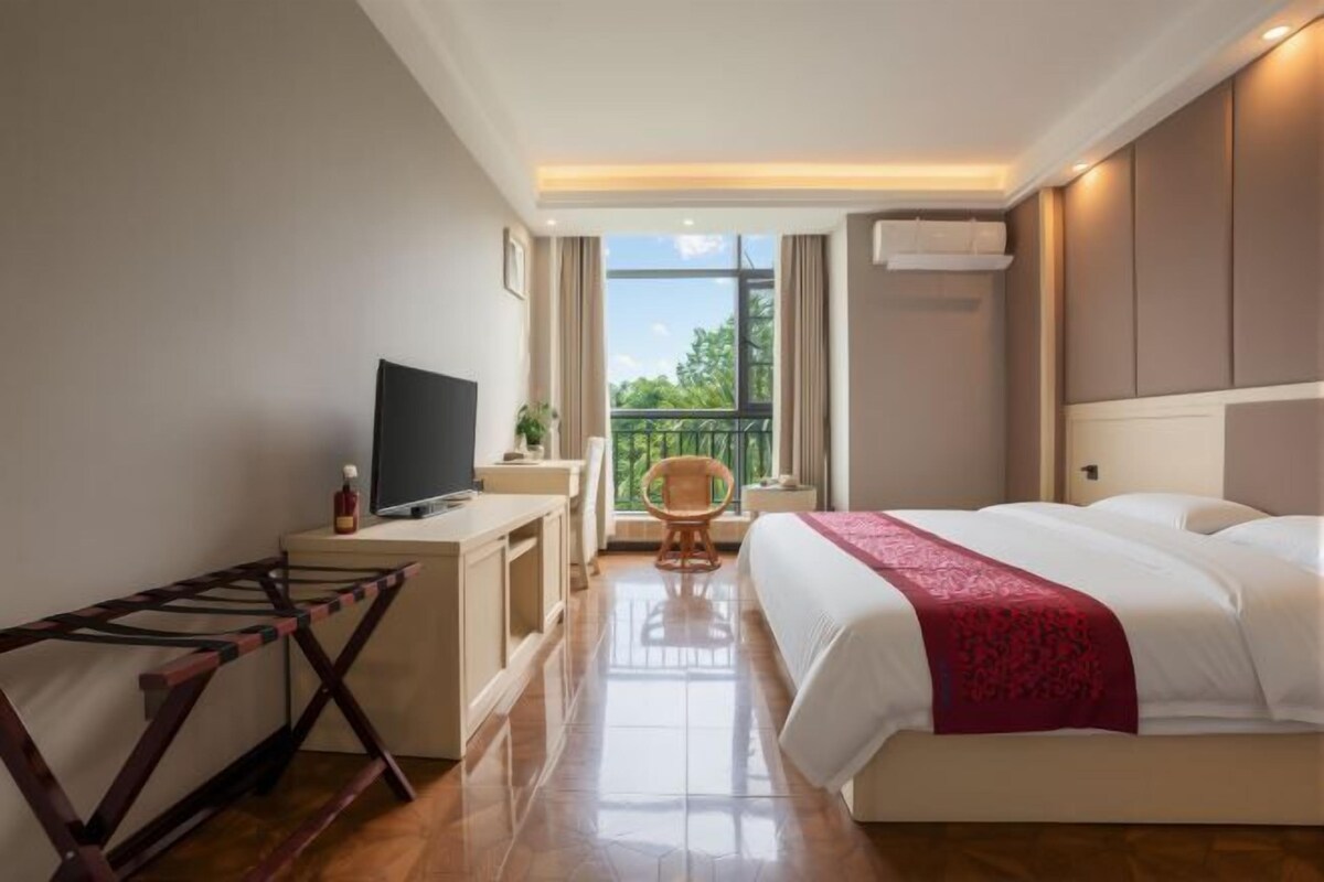 Une chambre d’hôtel avec un lit, une télévision, un bureau et un balcon.