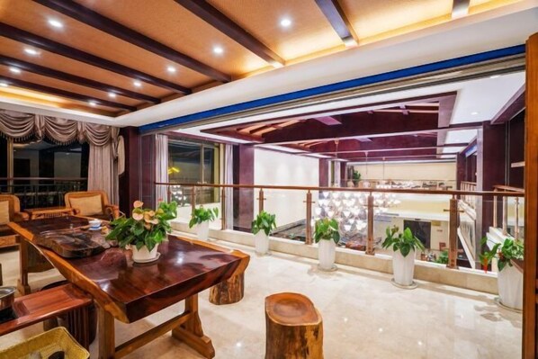 Un grand espace dédié à la salle à manger, avec une table en bois, des chaises et des plantes en pot.