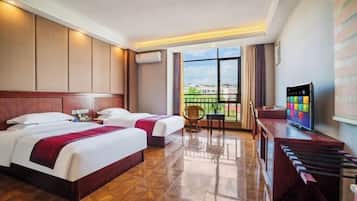 A hotel room with two beds, a TV, a desk, and a balcony with a view.