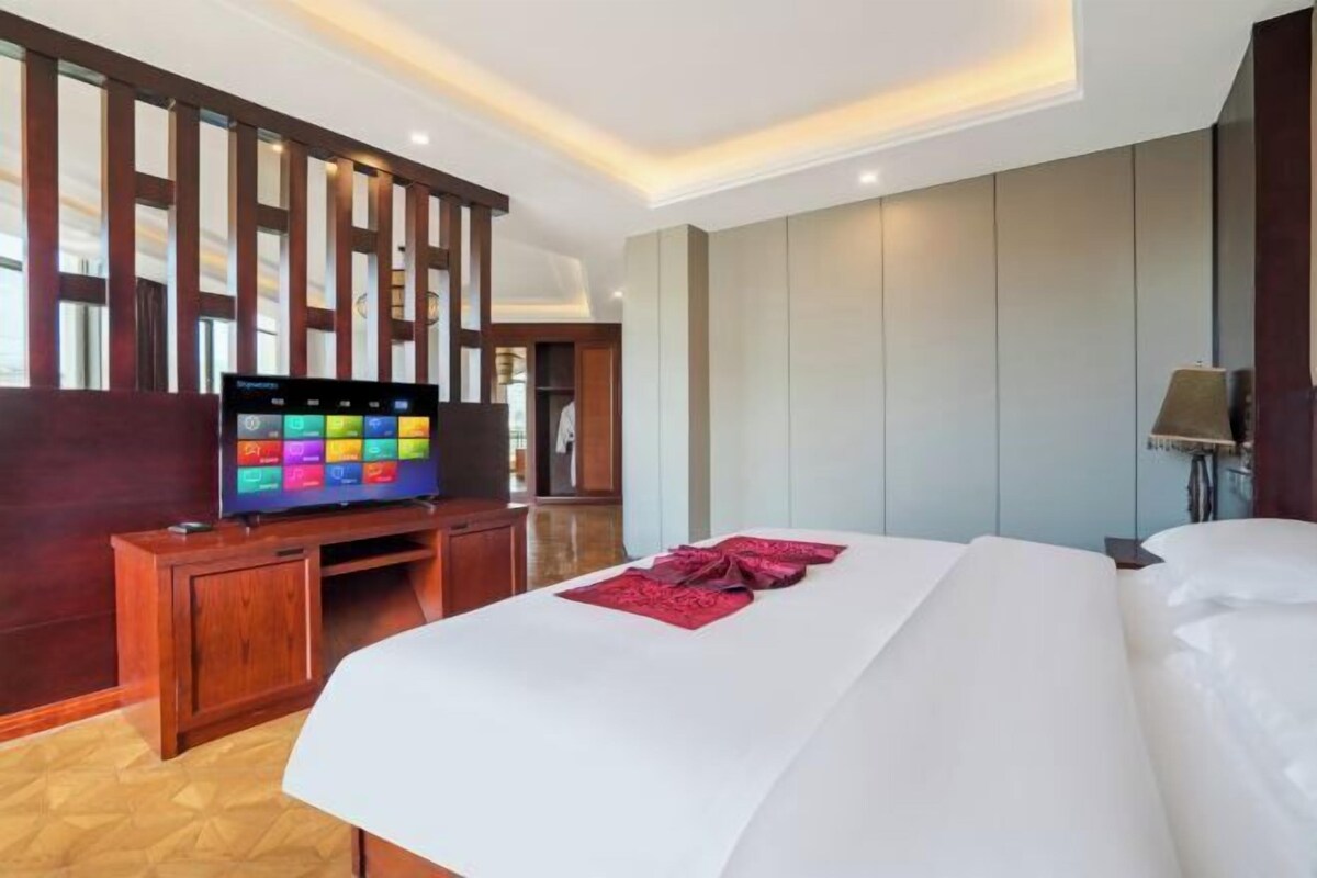 Une chambre d’hôtel avec un lit, un téléviseur posé sur un meuble en bois et un mur orné de panneaux en bois.