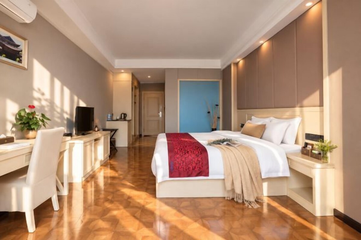 A hotel room with a bed, desk, chair, and a television.
