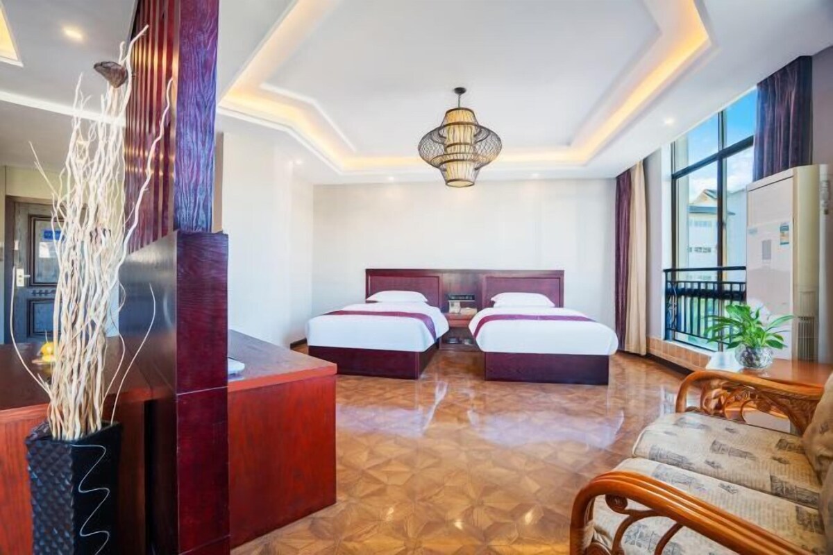 Une chambre d’hôtel avec deux lits, un comptoir d’accueil en bois, un vase décoratif et une grande fenêtre.