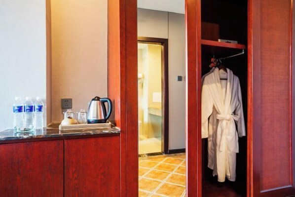 A bathroom with a wooden vanity, a kettle, and bottled water.