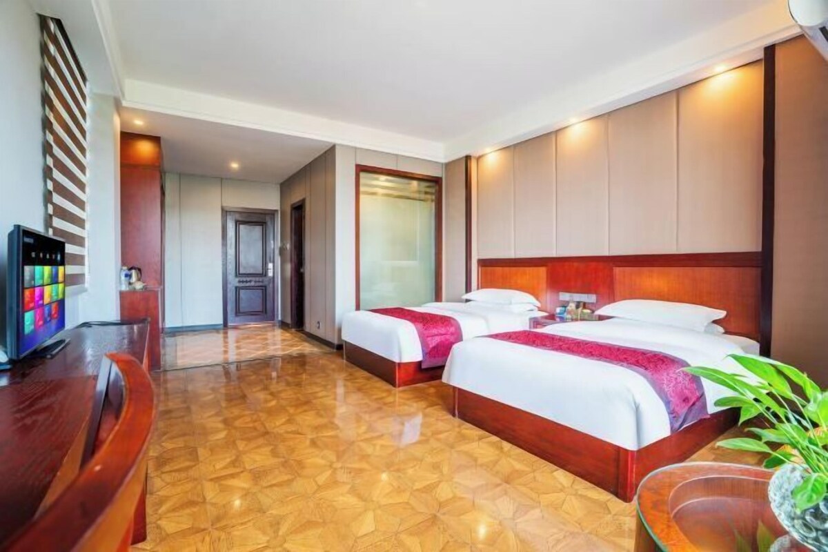 Une chambre d’hôtel avec deux lits, une télévision et un plancher en bois.