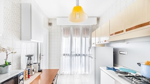 Una cocina moderna con armarios blancos, una encimera de madera, una estufa y una lámpara en el techo.