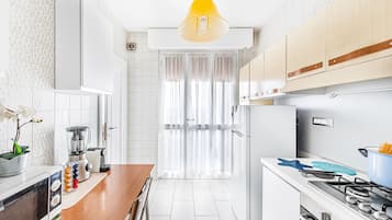 Una cucina moderna con mobili bianchi, un piano di lavoro in legno, un fornello e una luce a soffitto.