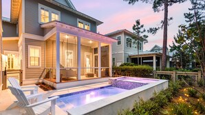 Een modern huis met een overdekte patio, een zwembad en een verzorgde tuin.
