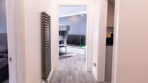 A narrow hallway with a radiator and a television in the background. - Luxury, Modern Apartment w/ Netflix in Zone 2 (London)