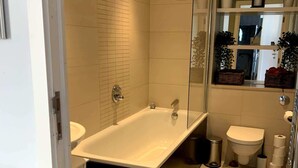 Une salle de bain moderne avec une baignoire sur pieds, une douche à parois de verre et des toilettes.