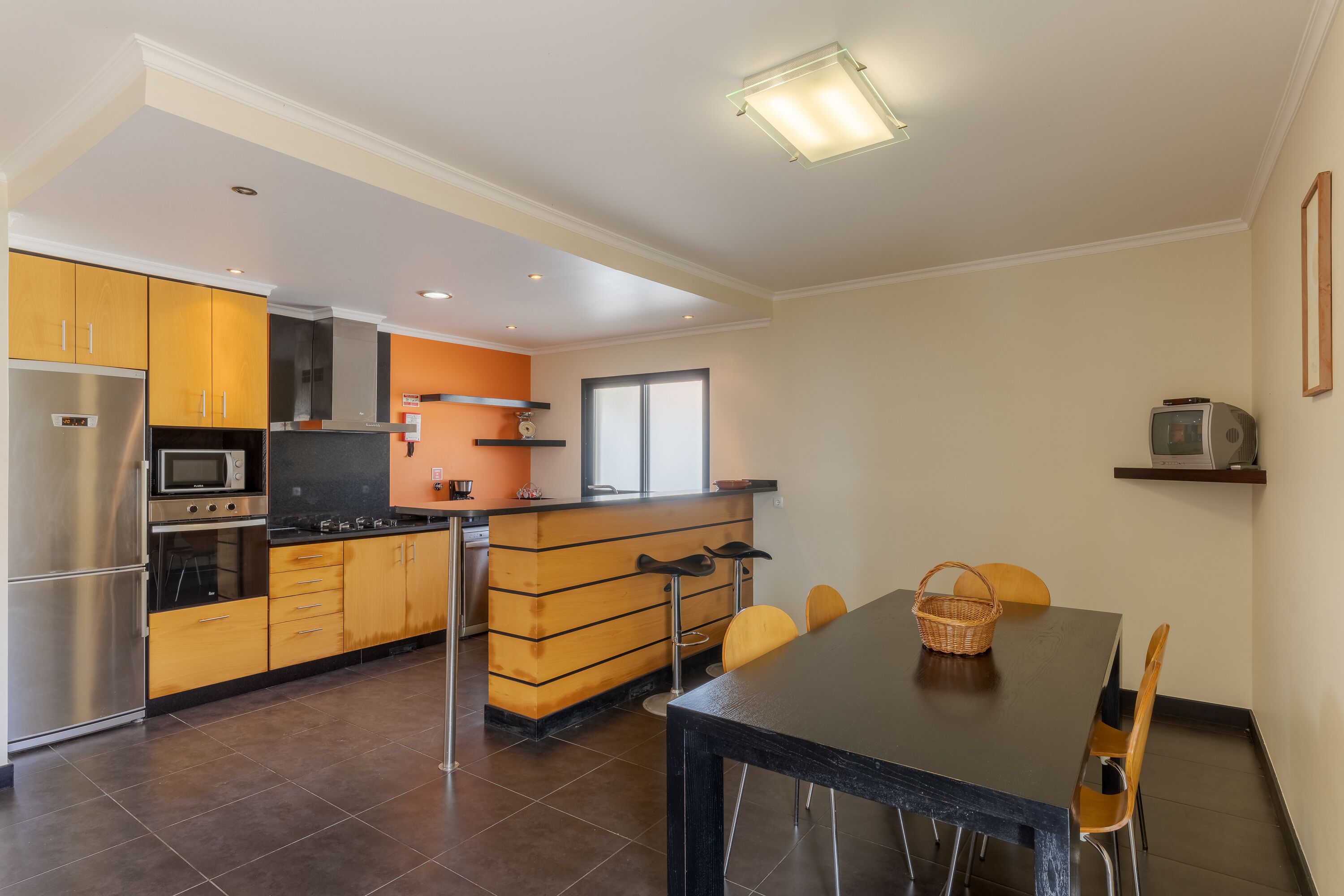A modern kitchen with stainless steel appliances, wooden cabinets, and a dining area with a table and chairs.