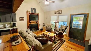 A cozy living room with a fireplace, a sofa, a coffee table, and a dining area with a wooden table and chairs. - GREAT EXPECTATIONS - 2 Bdrm/2 Bath, wood burning fireplace, secluded, Laurel Valley (Townsend)