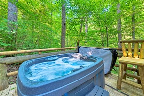 Un bain à remous sur une terrasse en bois, entouré d’une forêt.
