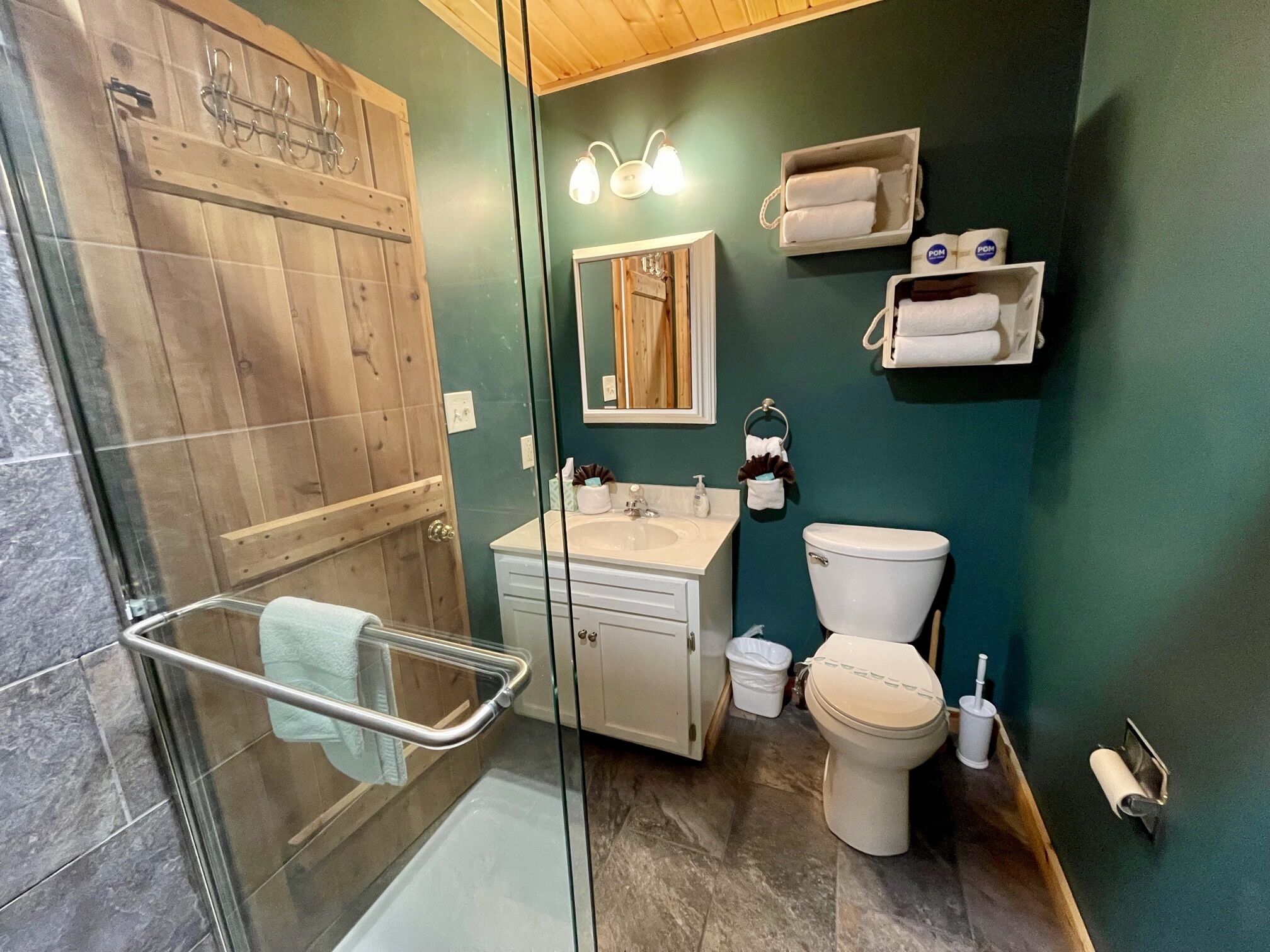 Un bany amb una cabina de dutxa de vidre, un lavabo blanc, un vàter i un mirall.
