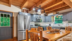 A modern kitchen with wooden cabinets, a stainless steel refrigerator, and a dining table with chairs. - GREAT EXPECTATIONS - 2 Bdrm/2 Bath, wood burning fireplace, secluded, Laurel Valley (Townsend)