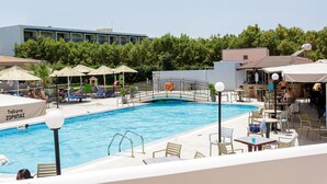 Ein Schwimmbecken mit Liegestühlen und Sonnenschirmen, umgeben von einer Poollandschaft mit Tischen und Stühlen.