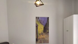 Ein Schlafzimmer mit einem Bett, einem weißen Kleiderschrank und einem Gemälde einer Straßenszene an der Wand.