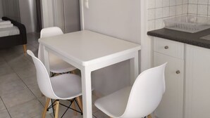Eine kleine, moderne Küche mit weißen Schränken, einem weißen Tisch und zwei weißen Stühlen.