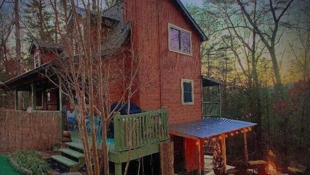 Ein rustikales Haus mit einer Holzdielen-Terrasse, einem Steinweg und einer Feuerstelle.