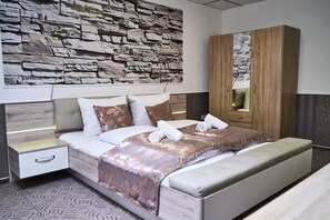 A modern bedroom with a stone wall, a wooden wardrobe, and a neatly made bed.