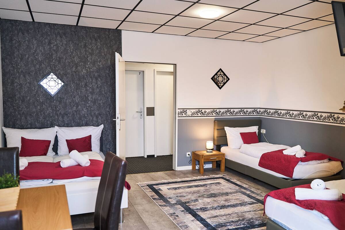 A hotel room with two beds, a desk, and a chair.