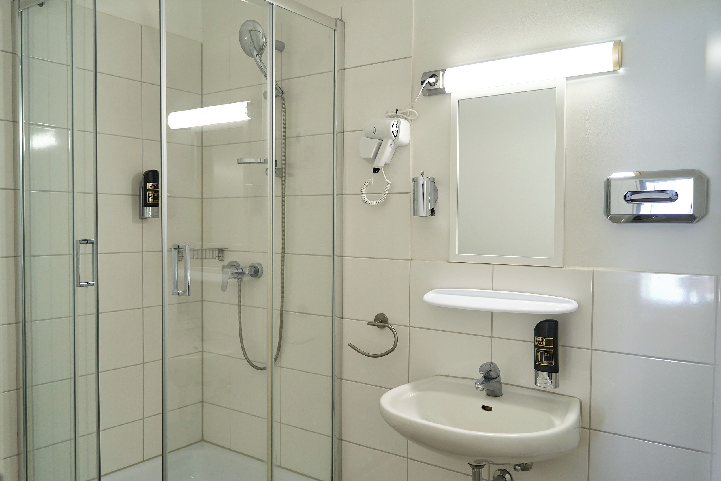 A modern bathroom with a glass-enclosed shower, a white sink, and a mirror.
