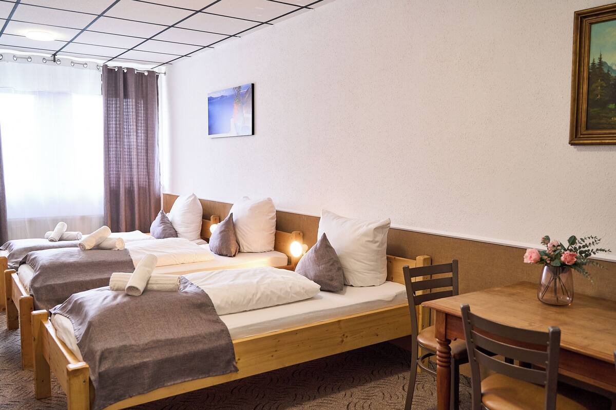 A hotel room with two wooden beds, a wooden table, and a chair.