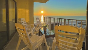 Ein Balkon mit Glastisch, Stühlen und einer Topfpflanze.