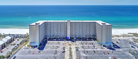 Et stort hotel med flere etager, parkeringsplads og havudsigt.