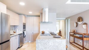 Una cocina moderna con encimeras de granito, electrodomésticos de acero inoxidable y una isla central.