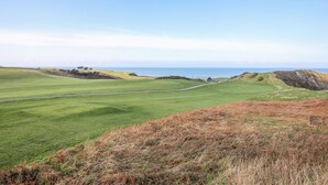 A golf course with a clear view of the ocean and distant hills. - Bwthyn Cerrig Man (Pwllheli)