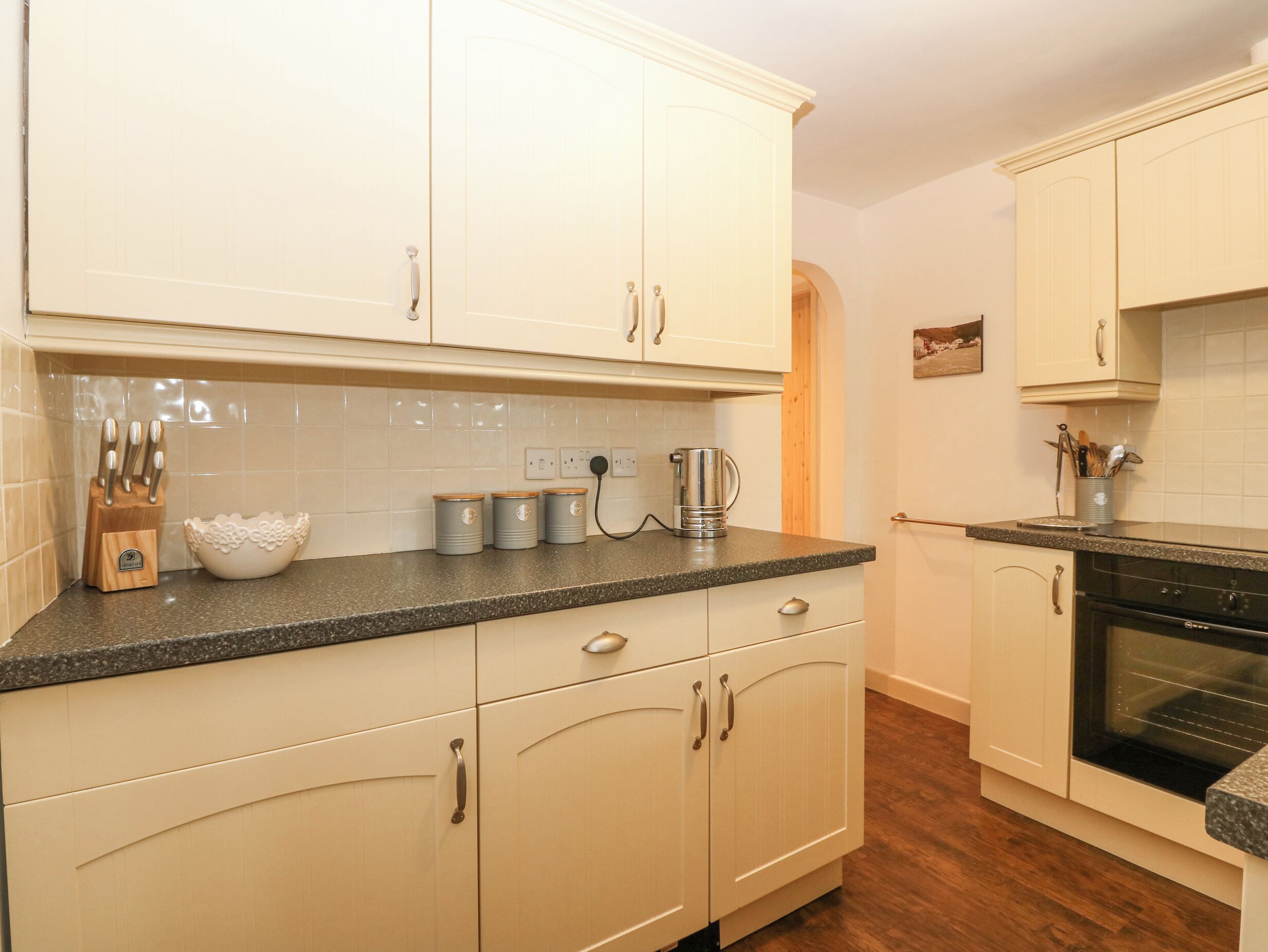 A kitchen with white cabinets, a granite countertop, and a black oven.
