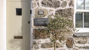 A stone wall with a door and a sign reading "Bwythyn Cerrig Ma". - Bwthyn Cerrig Man (Pwllheli)
