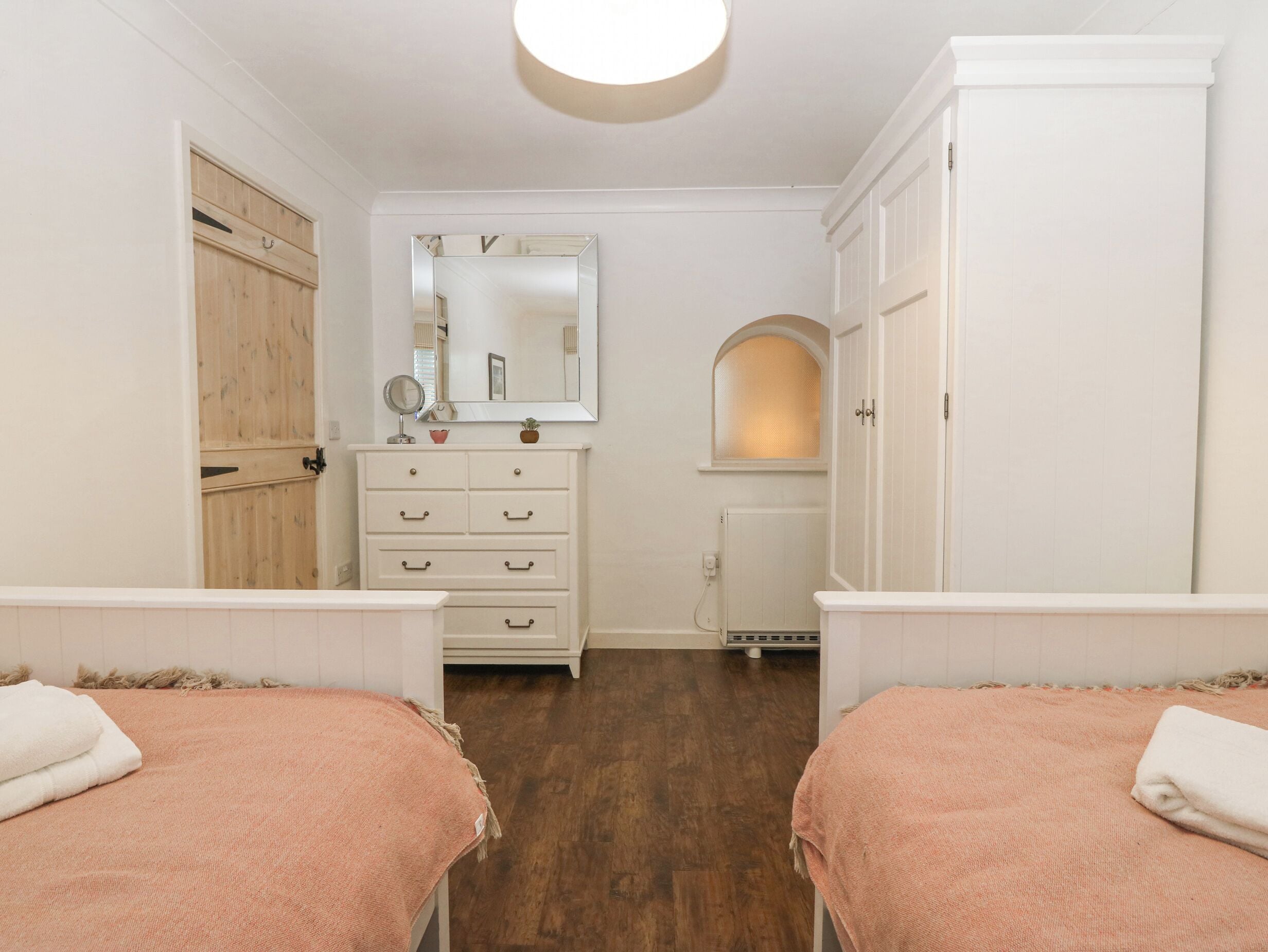 Een slaapkamer met twee bedden, een dressoir, een spiegel en een radiator.