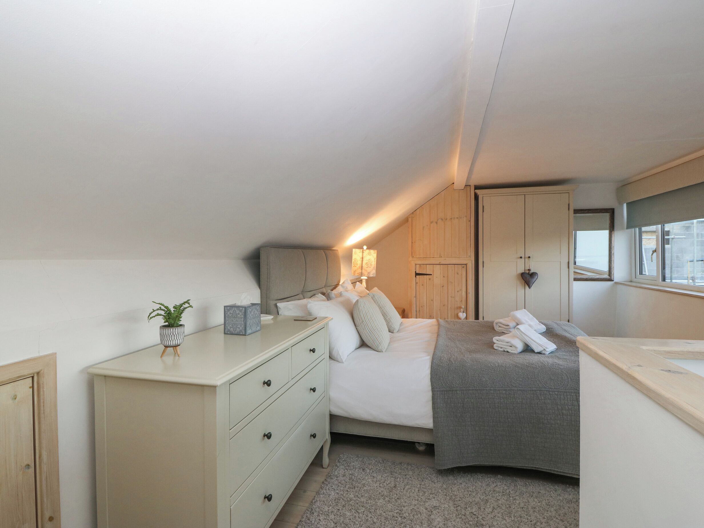 A bedroom with a bed, bedside table, lamp, and a window.